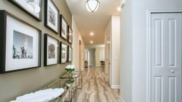 A hallway with framed pictures on the wall, a glass bench with a white towel, and a white door at the end. - Storey Lake 6 Bedroom Vacation Home 4712 (Osceola County)