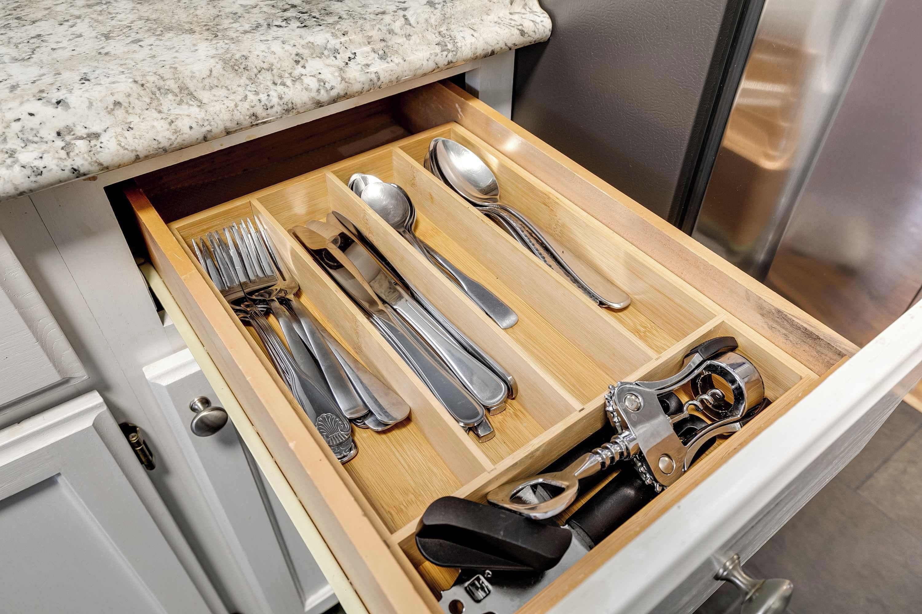Un cajón de cocina con utensilios y un abrelatas.