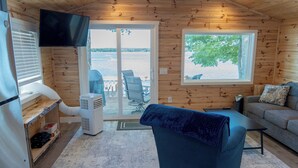 A cabin interior with a large window, a television, a sofa, and a chair.