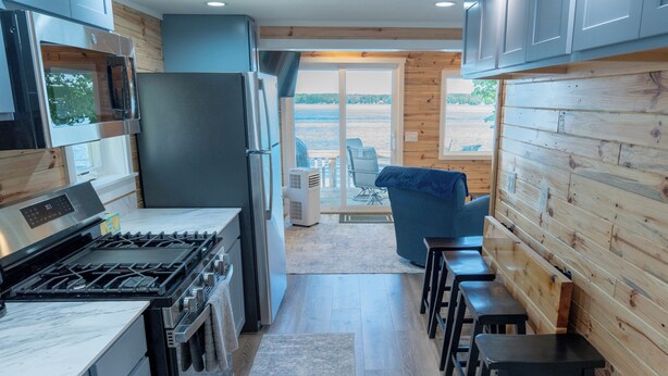 A modern kitchen with a gas stove, stainless steel appliances, and wooden paneling.