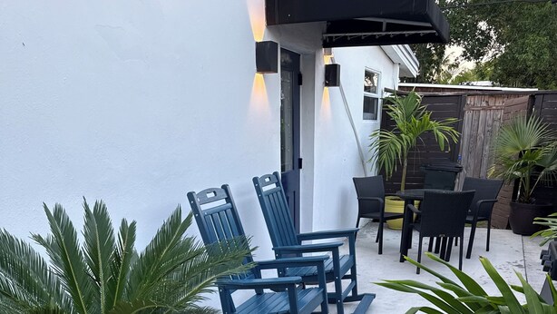 Un patio con mobiliario exterior, una planta en maceta y un sendero de hormigón.