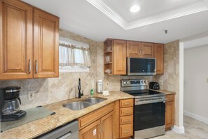 A kitchen with wooden cabinets, a stainless steel sink, a microwave, an oven, and a coffee maker. - 🌊 New Listing! Caprice Resort Unit #305 – Gulf Front Comfort with Private Balcony (Saint Pete Beach)