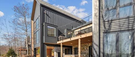 A modern two-story house with a covered patio and a stone facade.