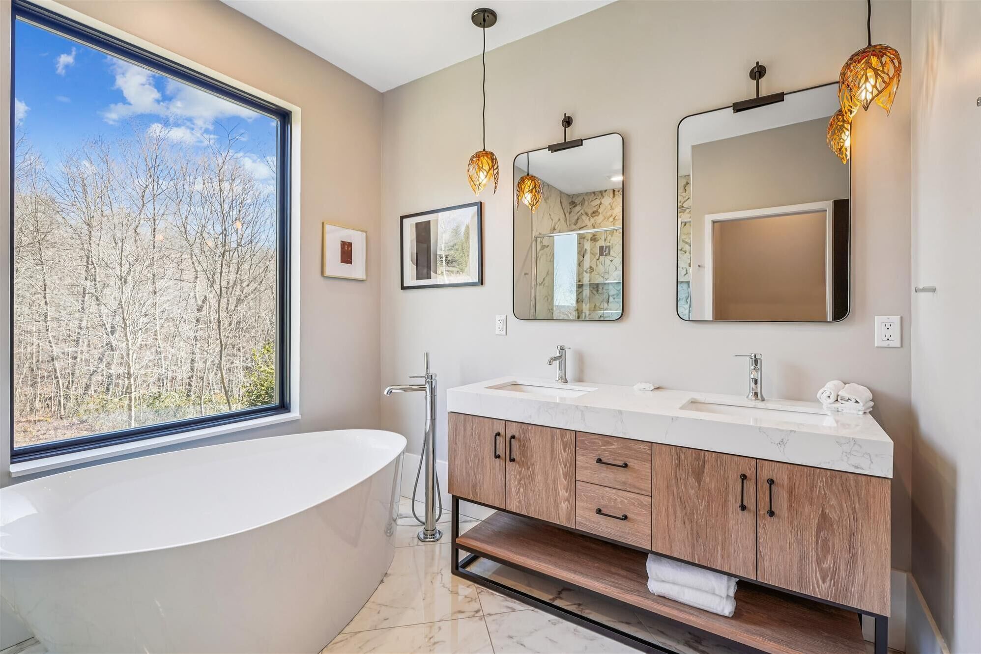 Une salle de bain moderne avec une baignoire sur pieds, deux vasques et un grand miroir.