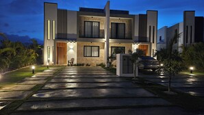 Une maison moderne à deux étages, dotée d’une façade en pierre, d’une allée menant à l’entrée et d’une voiture garée dans l’allée.