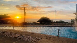 Una piscina con vista sul tramonto, una recinzione e un lampione.