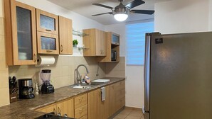 A kitchen with wooden cabinets, a stainless steel refrigerator, a double sink, a coffee maker, and a blender.