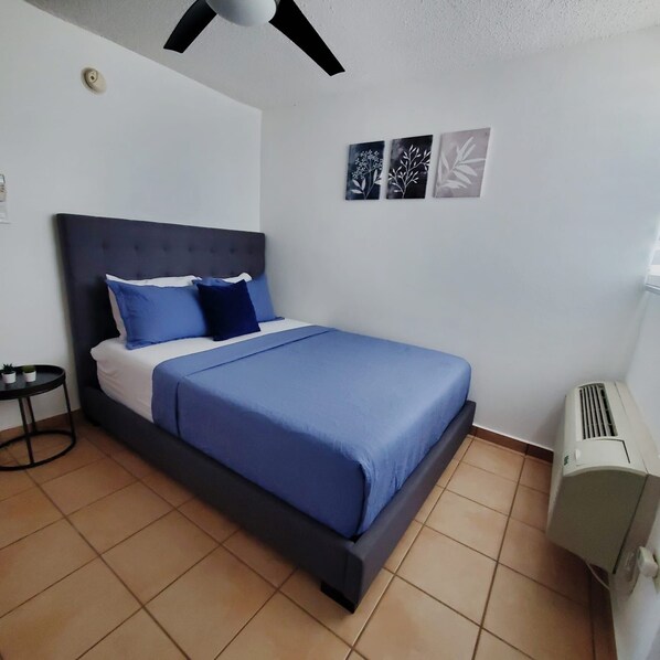 Une chambre à coucher avec un lit, une petite table et un climatiseur fixé au mur.