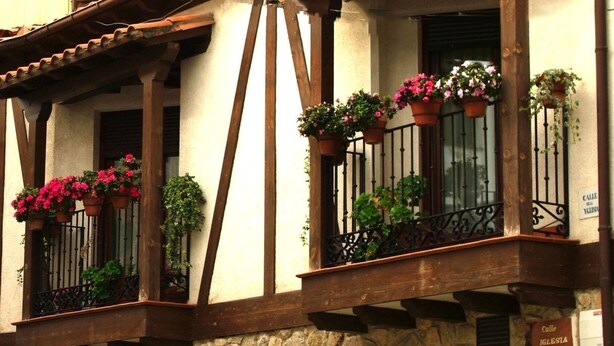 Ein Steingebäude mit einem Balkon, der mit Blumentöpfen und Blumen geschmückt ist.