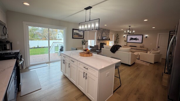 Een moderne keuken met een groot eiland, een eethoek met een witte tafel en een woonkamer met een bank en televisie.
