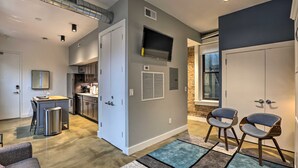 A modern kitchen with a built-in oven, a dining area with a table and chairs, and a living area with a TV and seating. - Sleek Studio Near Dtwn Dining & Entertainment (Cincinnati)