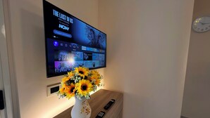 A flat-screen TV mounted on a wall displaying a movie poster for "The Last of Us". - Suite Apartment Shuttle • Beach • Garden • WiFi • AirCondition • FreeParking (Nocera Scalo)