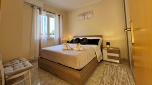 A neatly arranged bedroom with a bed, bedside table, lamp, and a chair. - Suite Apartment Shuttle • Beach • Garden • WiFi • AirCondition • FreeParking (Nocera Scalo)