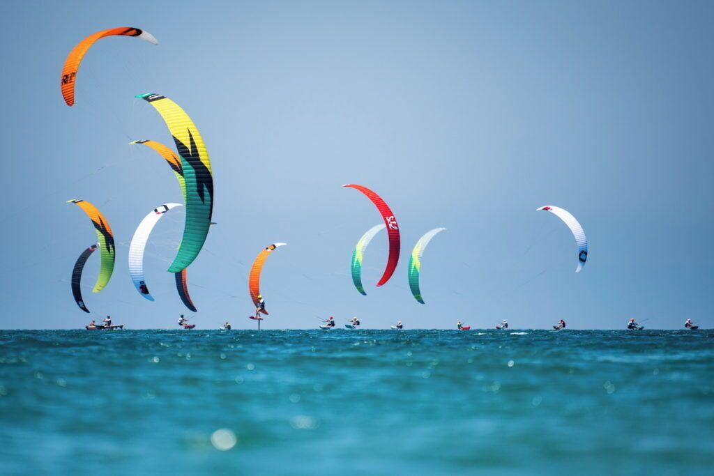 A group of parasailers on the water with colorful parasails.