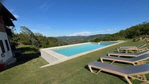 A rectangular pool with clear blue water, surrounded by artificial grass, and a few lounge chairs. - Panoramic Estate in the Langhe with Pool - Up to 12 Guests, Ideal for Groups (Piemonte)