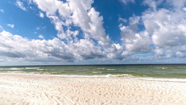 A beach with a sandy shore and a view of the ocean under a partly cloudy sky. - Welcoming 3-bedroom house in sunny Naples: Beach Days Made Easy (Naples)