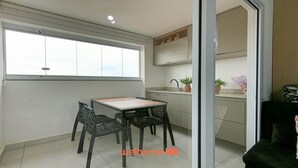 Un espacio habitable compacto con comedor, kitchenette y un amplio ventanal.