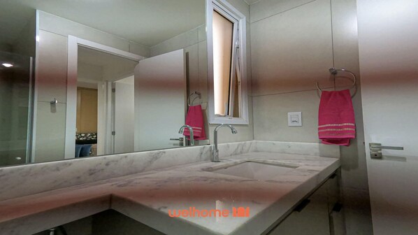 A modern bathroom with a large mirror, a sink, and a window.