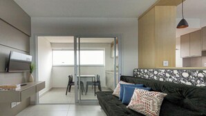 Una sala de estar moderna con sofá, televisión y un comedor con sillas y una mesa.