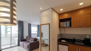 Un apartamento moderno con kitchenette, un sofá, una mesa de comedor y un ventanal grande.
