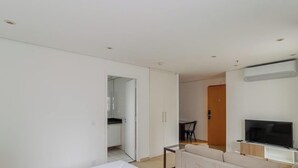Een moderne woonkamer met een bank, een televisie en een eethoek met een tafel en stoelen.