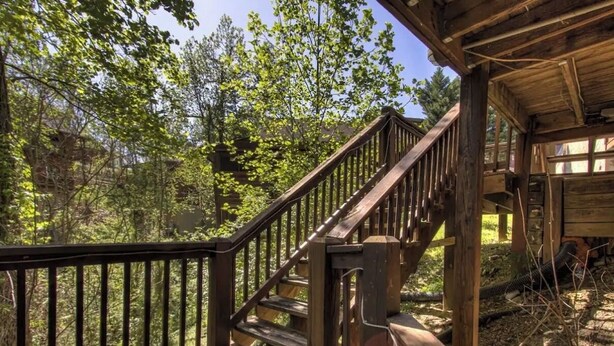 A wooden staircase leading to a cabin with a view of a forest. - Affordable Pigeon Forge Cabin 1 Mile to Strip! (Pigeon Forge)