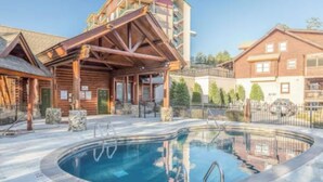 A pool area with wooden buildings and a covered seating area. - Affordable Pigeon Forge Cabin 1 Mile to Strip! (Pigeon Forge)