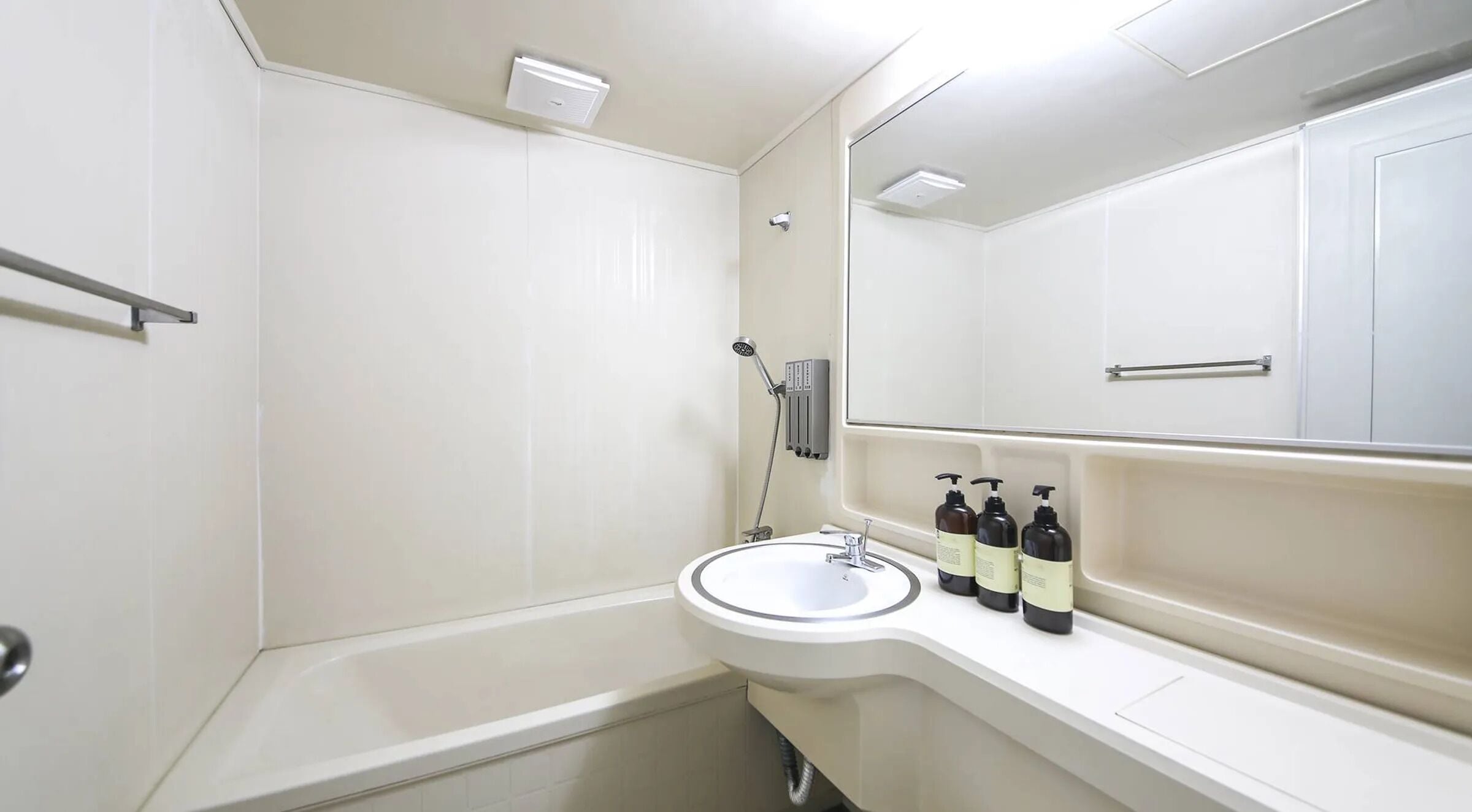A modern bathroom with a white sink, mirror, and shower.
