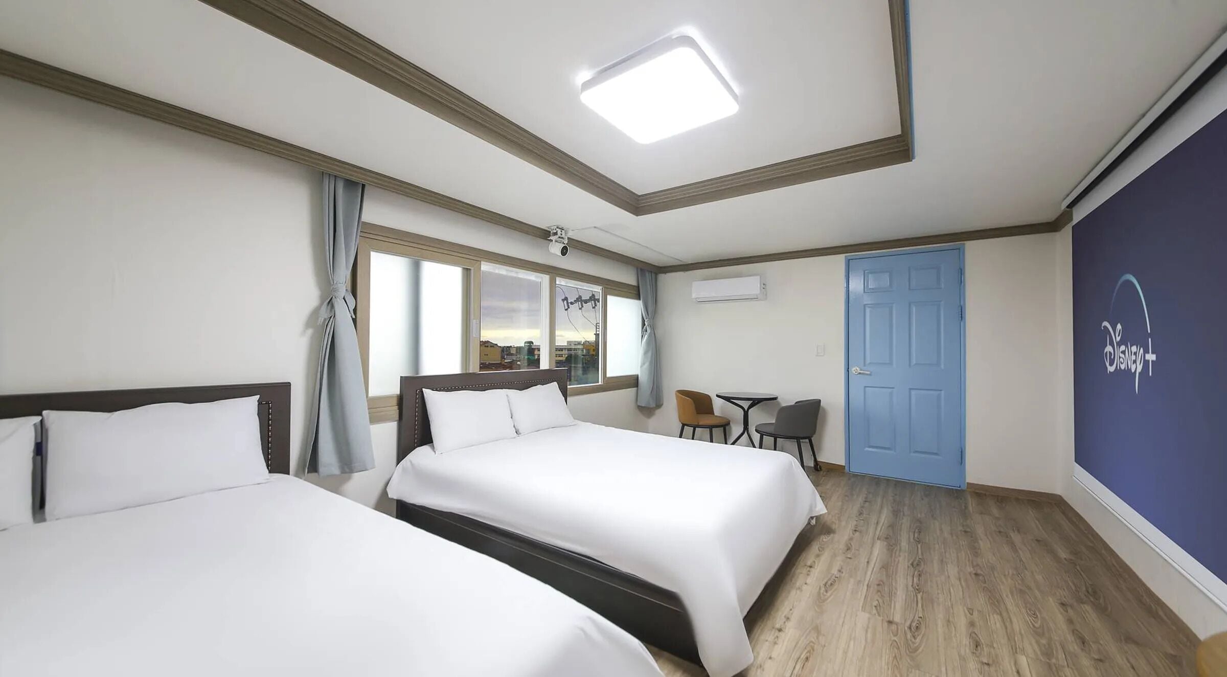 A hotel room with two beds, a desk, and a chair.