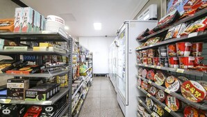 A narrow aisle in a store with shelves stocked with various packaged goods, including snacks and beverages. - Top Island Hotel (Jeju City)