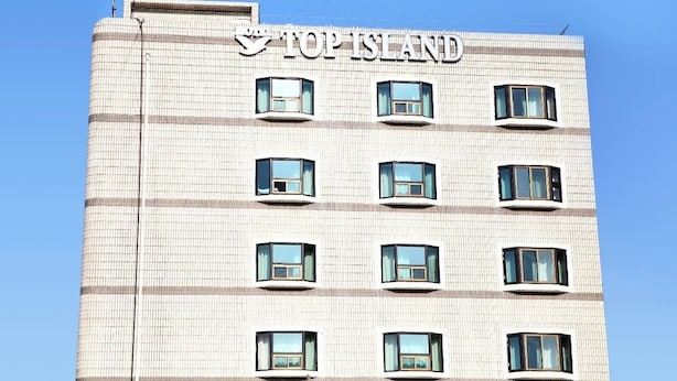 A multi-story building with the name "TOP ISLAND" prominently displayed on the facade. - Top Island Hotel (Jeju City)