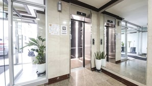 A modern hotel lobby with glass doors, potted plants, and an elevator. - Top Island Hotel (Jeju City)
