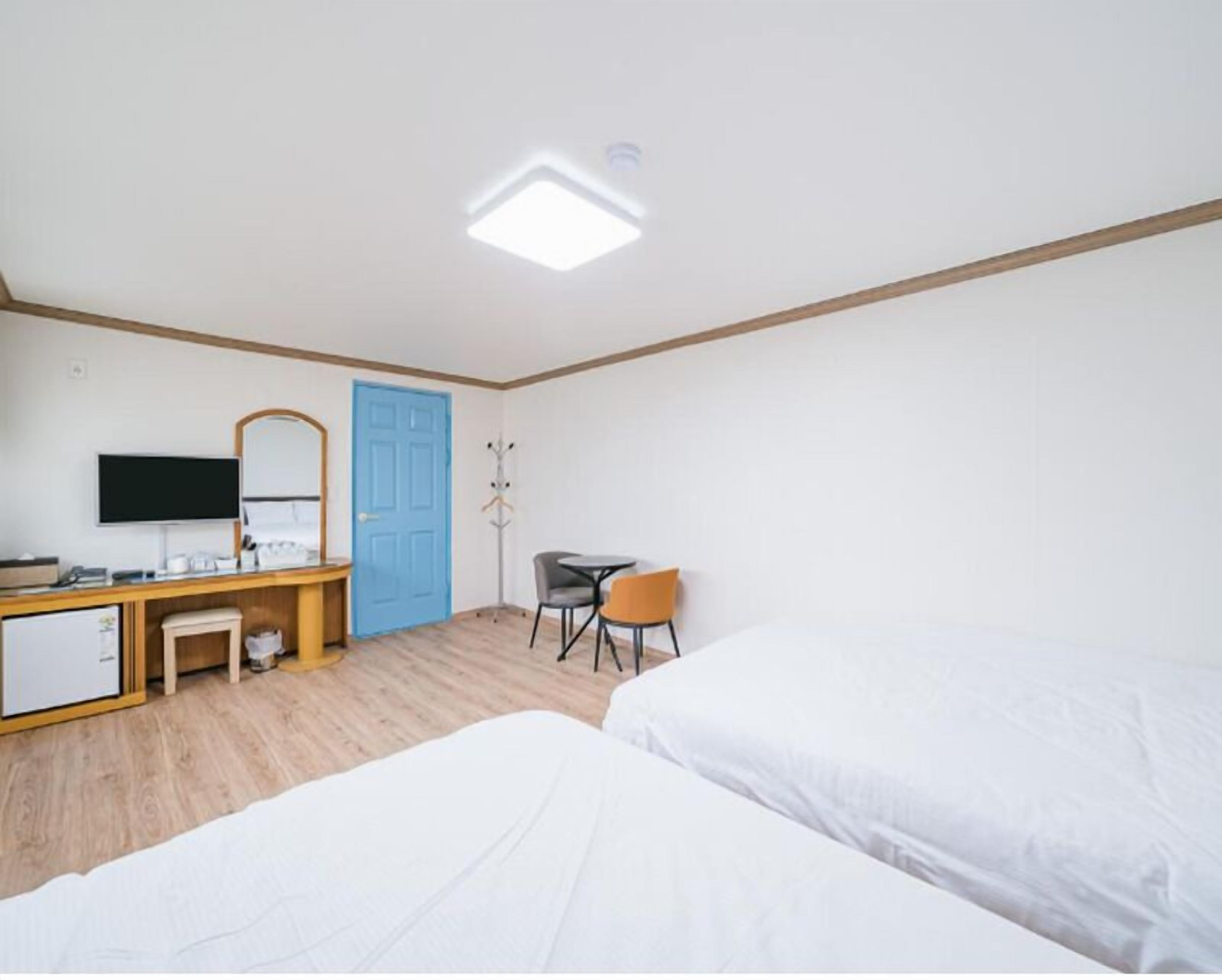 Quarto de hotel com uma cama, uma escrivaninha com um computador, uma cadeira e uma televisão.