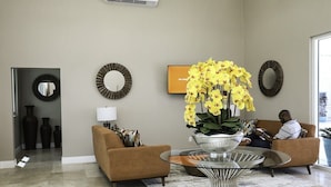 Un soggiorno moderno con un divano, un tavolino in vetro con un'esposizione di fiori e specchi decorativi alle pareti.