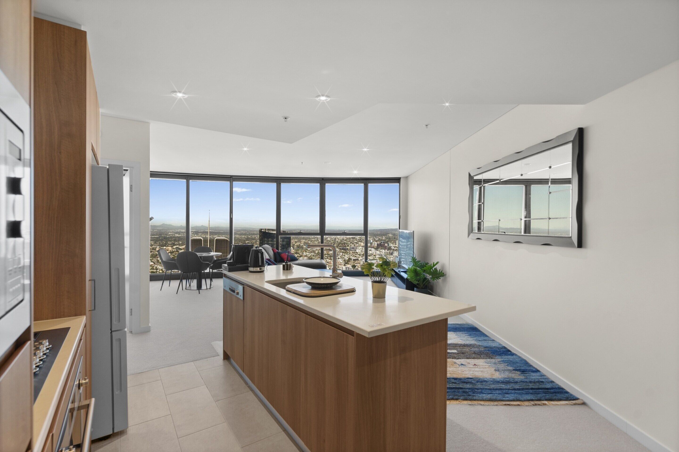 A modern kitchen with a large island, a dining area with a view, and a large window.