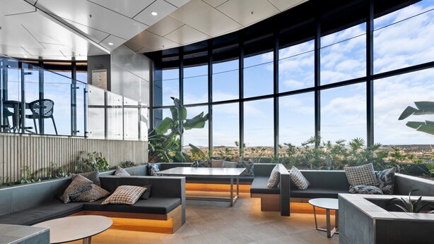 Un espace de détente moderne doté d’un mur incurvé en verre, de différents types de sièges et offrant une vue sur le paysage urbain.