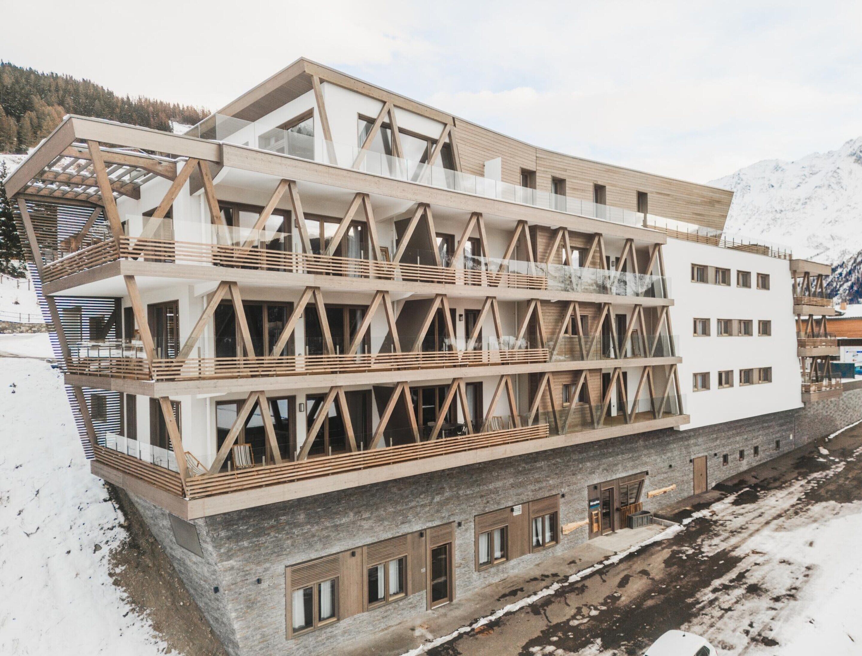 Un immeuble à plusieurs étages doté d’une façade en bois, de grandes fenêtres et de balcons.
