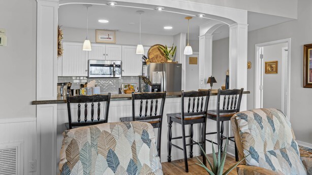 Una cocina moderna con armarios blancos, una isla central con taburetes y luces colgantes.