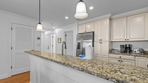 Una cocina moderna con encimeras de granito, electrodomésticos de acero inoxidable y armarios blancos.