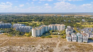Zona residencial costera con edificios de varios pisos, incluyendo un hotel grande con balcones y una playa en primer plano.