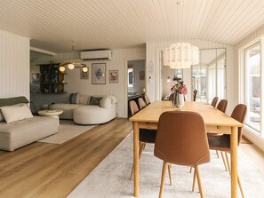 A modern living space with a dining area, a sofa, and a kitchen in the background. - 4 Star Holiday Home in Dannemare (Dannemare)