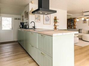 A kitchen with a central island, a black range hood, and a window. - 4 Star Holiday Home in Dannemare (Dannemare)