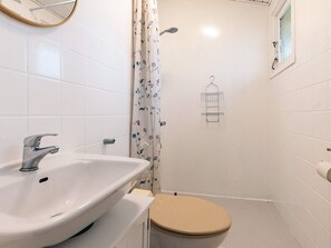 A bathroom with a sink, toilet, shower, and a hanging towel rack. - 4 Star Holiday Home in Dannemare (Dannemare)