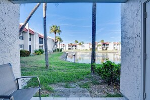 A view from a balcony overlooking a courtyard with a water feature, palm trees, and buildings in the background. - Hello Darling at Runaway Bay 177 (Bradenton Beach)