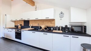 Una cucina moderna con mobili bianchi, un piano di lavoro nero e una schiena di legno.