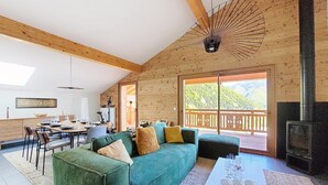 Un accogliente chalet con un divano verde, zona pranzo e camino.
