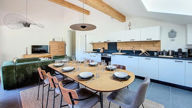 Una cucina moderna con mobili bianchi, un tavolo da pranzo in legno e un forno integrato.