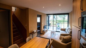 A modern kitchen with wooden cabinets, a dining area with a table and chairs, and a staircase leading to another level. - Mountain-view Eco-friendly Cottage (Marcoux)