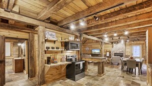 A rustic wooden interior with a kitchen area, a dining table, and a bar. - Hocking Hills: Timber Bear Lodge (McArthur)