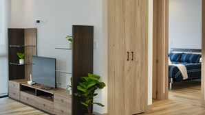 A modern living room with a flat-screen TV, wooden cabinets, and a potted plant. - Apartments in Cumbaya near Airport (Cumbayá)